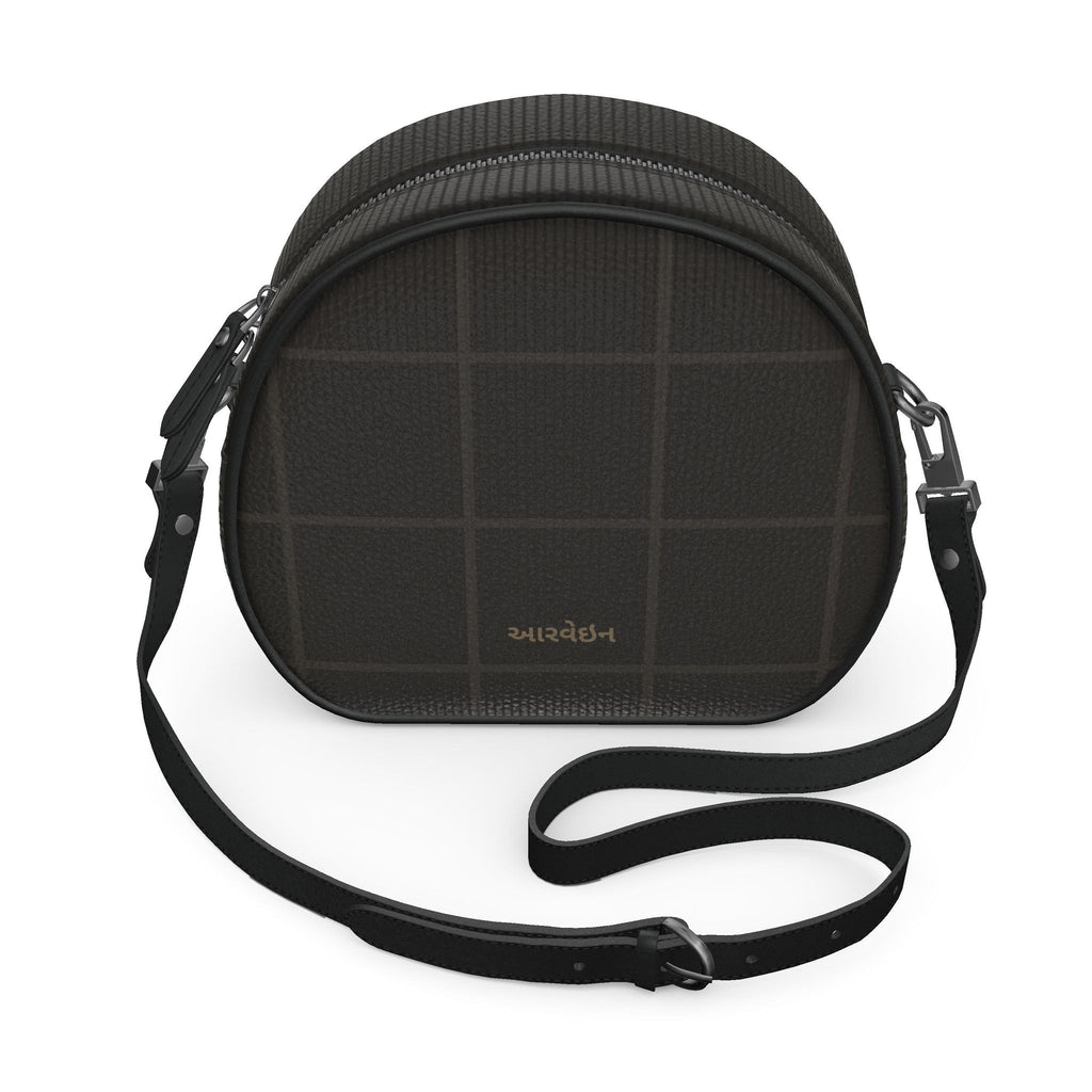 Peacock in Disguise grid round box bag in black nappa leather with a tonal grid pattern and crossbody strap, angled front
