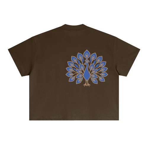 Back of the brown boxy tee with a large blue-and-gold embroidered peacock, tail fanned open, placed off-centre