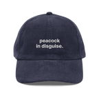 Corduroy cap in navy, front, with “peacock in disguise.” embroidered in white